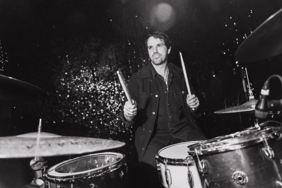 Jared Tredly playing drums on stage, black and white